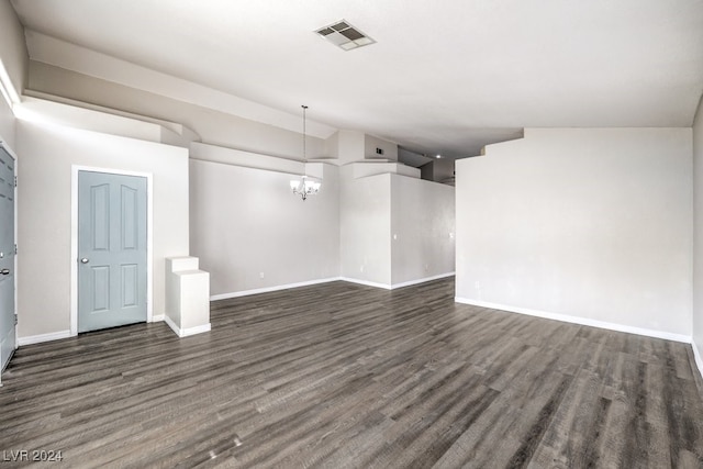 empty room with lofted ceiling, dark hardwood / wood-style floors, and an inviting chandelier