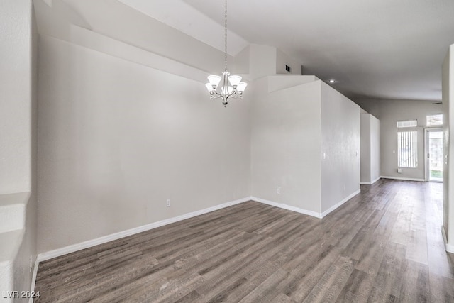 empty room featuring dark hardwood / wood-style floors, an inviting chandelier, and lofted ceiling