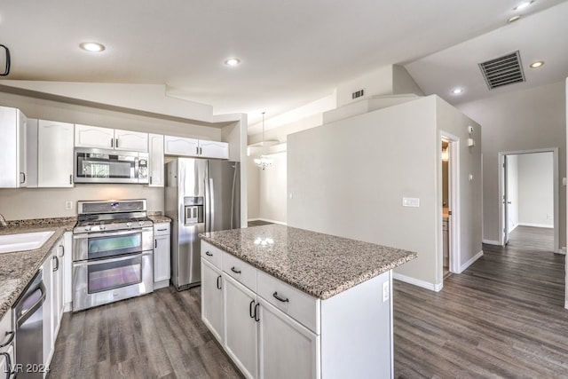 kitchen featuring white cabinetry, a center island, stainless steel appliances, and lofted ceiling