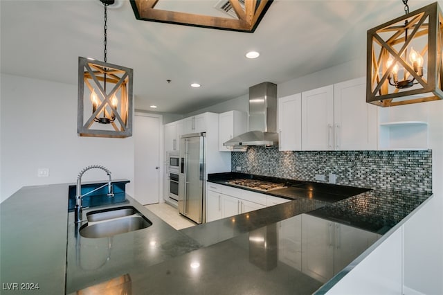 kitchen featuring wall chimney exhaust hood, pendant lighting, and white cabinets