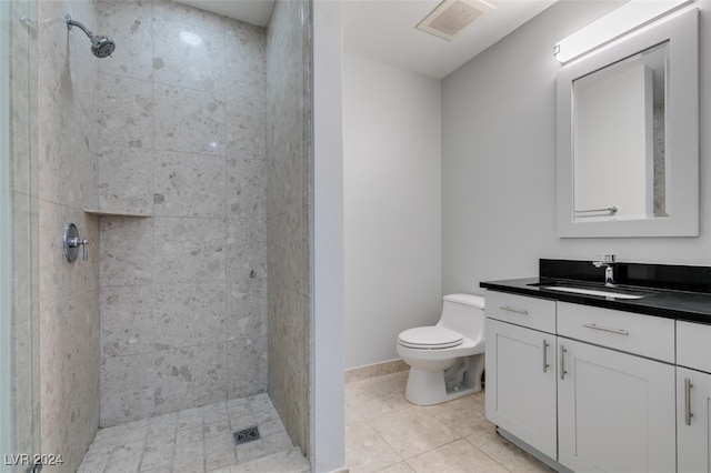 bathroom with vanity, toilet, tile patterned floors, and tiled shower