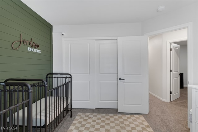 carpeted bedroom with a closet and a crib