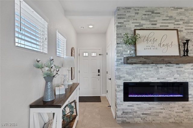 doorway with a stone fireplace and tile patterned flooring