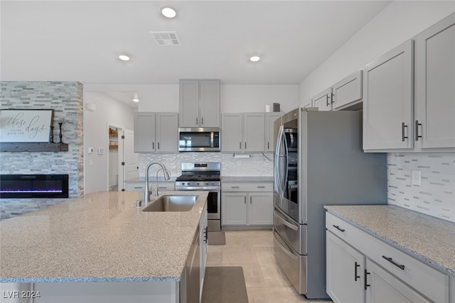 kitchen with tasteful backsplash, stainless steel appliances, sink, and light stone counters