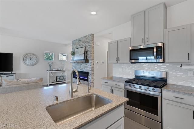 kitchen featuring tasteful backsplash, stainless steel appliances, sink, and light stone counters