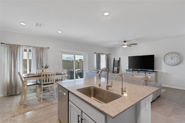 kitchen featuring sink, an island with sink, ceiling fan, stainless steel dishwasher, and light tile patterned floors