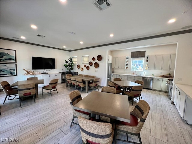 dining space with crown molding and sink