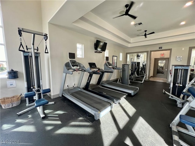 workout area with ceiling fan and a raised ceiling