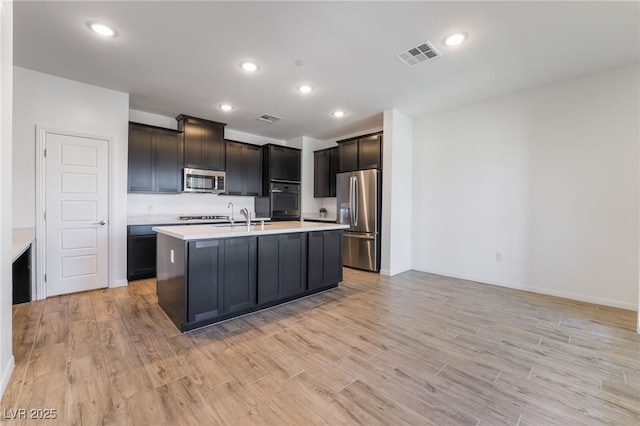 kitchen featuring a center island with sink, sink, stainless steel appliances, and light hardwood / wood-style flooring