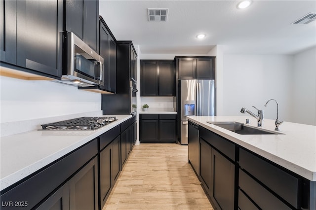 kitchen with sink, light stone counters, stainless steel appliances, and light hardwood / wood-style floors