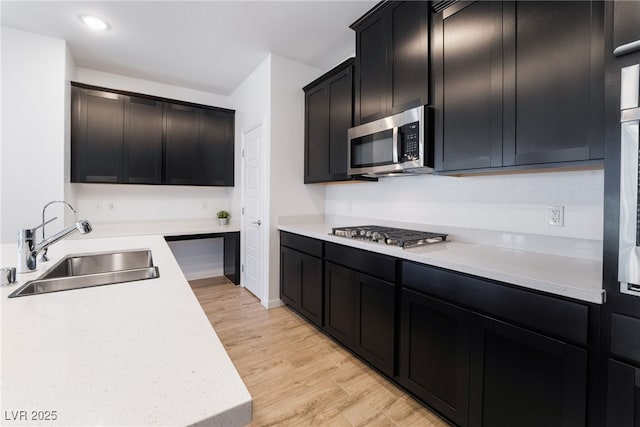 kitchen with appliances with stainless steel finishes, sink, and light hardwood / wood-style flooring