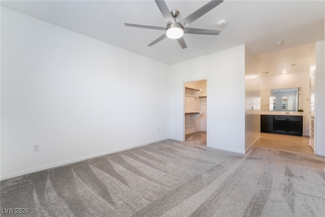 unfurnished bedroom featuring a spacious closet, ceiling fan, a closet, and light colored carpet