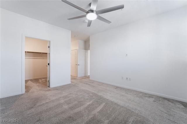 unfurnished bedroom featuring a spacious closet, light colored carpet, a closet, and ceiling fan