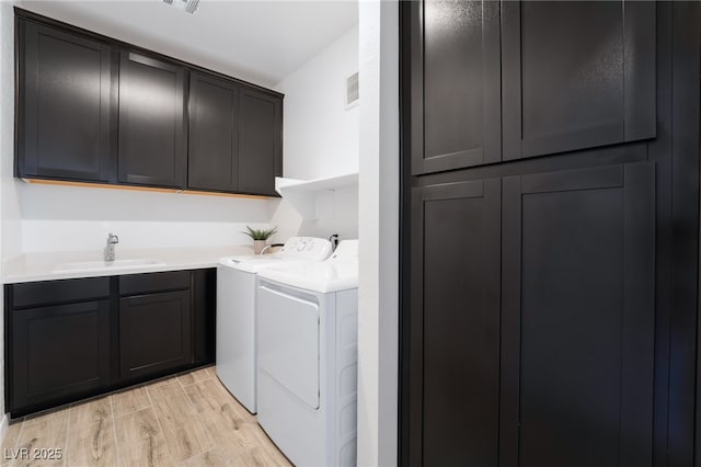 washroom with independent washer and dryer, sink, and cabinets