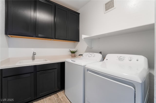 laundry area featuring cabinets, washer and clothes dryer, and sink