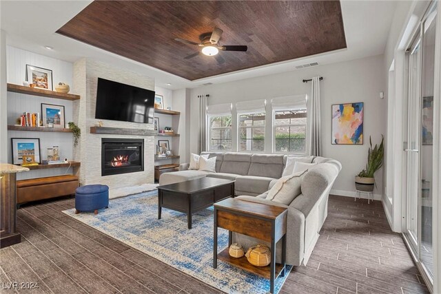 living room featuring ceiling fan, a fireplace, wooden ceiling, and dark hardwood / wood-style flooring