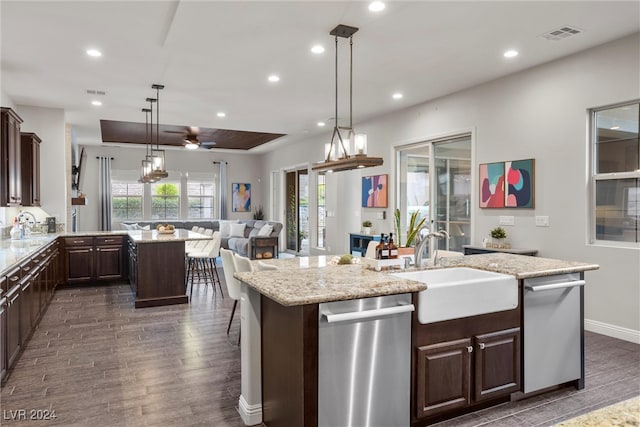 kitchen with sink, dishwasher, an island with sink, dark hardwood / wood-style flooring, and hanging light fixtures