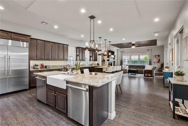 kitchen with a large island with sink, dark hardwood / wood-style floors, stainless steel appliances, sink, and dark brown cabinetry