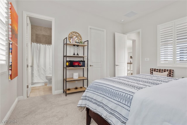 bedroom featuring connected bathroom and light colored carpet