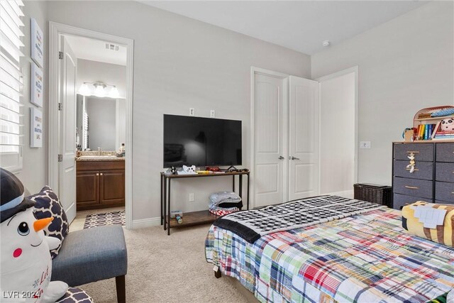 bedroom featuring connected bathroom, light carpet, a closet, and sink