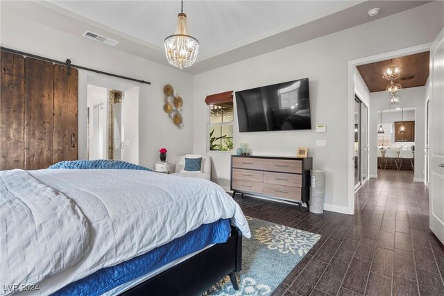 bedroom featuring an inviting chandelier, a barn door, and dark hardwood / wood-style flooring