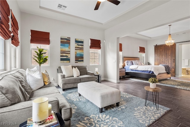 bedroom with dark hardwood / wood-style floors, a barn door, and ceiling fan