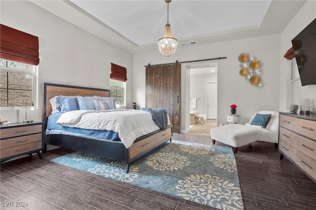 bedroom featuring a tray ceiling, dark hardwood / wood-style flooring, and a barn door