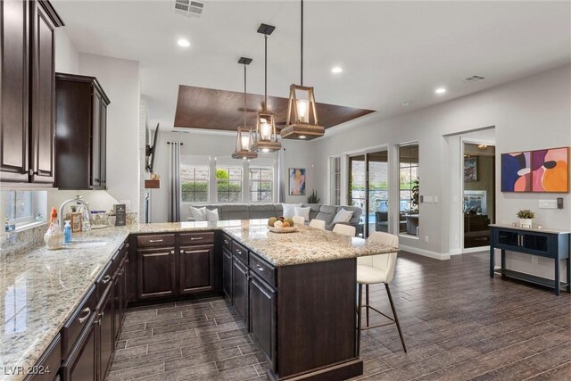 kitchen featuring a kitchen breakfast bar, hanging light fixtures, dark wood-type flooring, and plenty of natural light