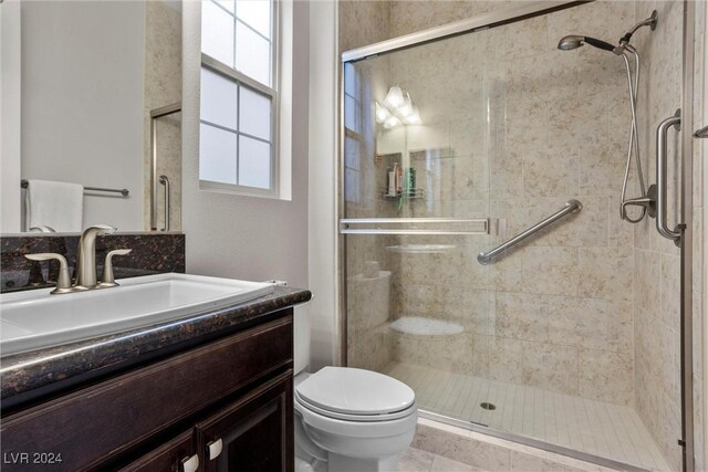 bathroom featuring vanity, toilet, a shower with shower door, and a wealth of natural light