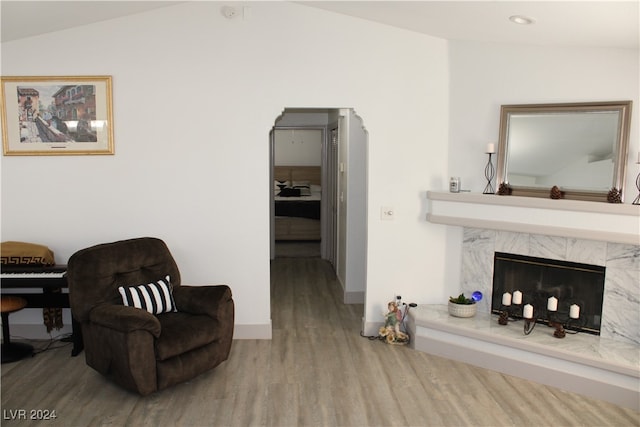 living area featuring lofted ceiling, a high end fireplace, and hardwood / wood-style floors