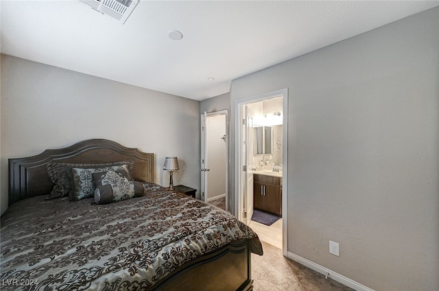 bedroom featuring ensuite bathroom and light colored carpet