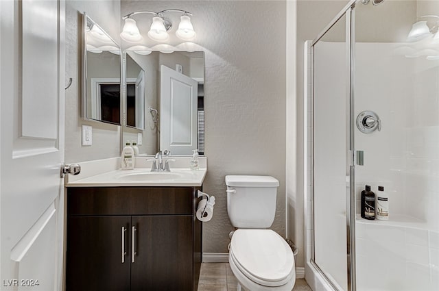 bathroom featuring toilet, walk in shower, vanity, and tile patterned floors