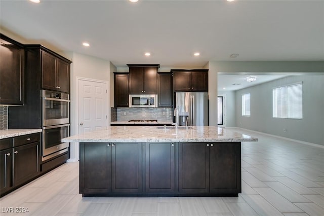 kitchen with stainless steel appliances, a kitchen island with sink, dark brown cabinets, and sink