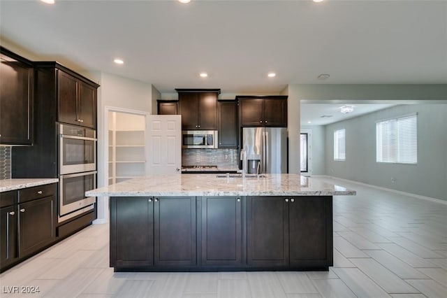 kitchen with a kitchen island with sink, dark brown cabinets, and stainless steel appliances