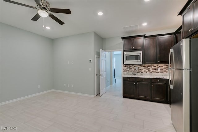 kitchen with ceiling fan, decorative backsplash, dark brown cabinetry, appliances with stainless steel finishes, and light stone countertops