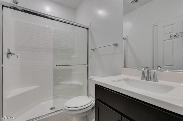 bathroom with a shower with shower door, toilet, and vanity