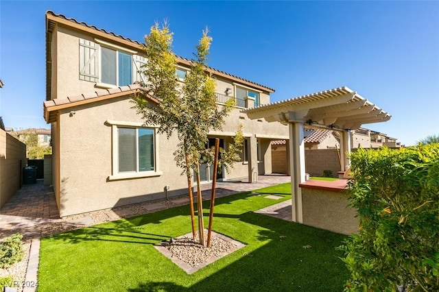 rear view of property featuring a yard, a pergola, and a patio