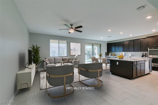 living room with ceiling fan, sink, and light hardwood / wood-style flooring