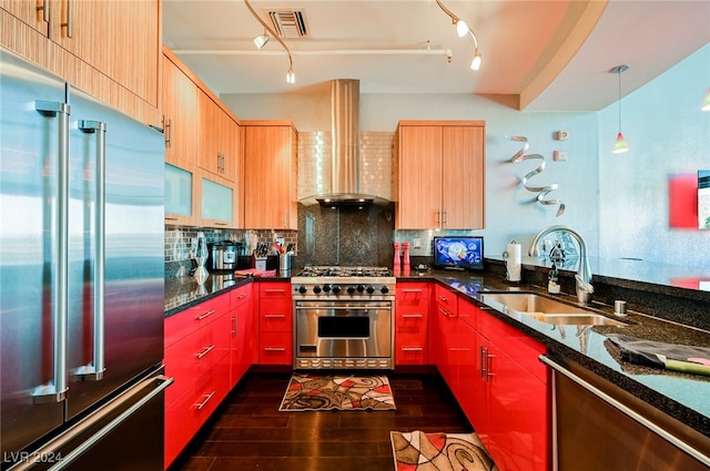 kitchen featuring dark hardwood / wood-style flooring, sink, wall chimney exhaust hood, decorative light fixtures, and premium appliances