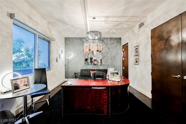 office with dark hardwood / wood-style flooring and an inviting chandelier