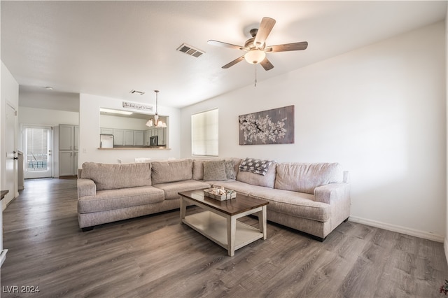 living room with ceiling fan with notable chandelier and dark hardwood / wood-style flooring