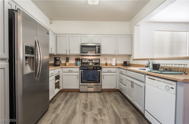 kitchen with light hardwood / wood-style flooring, stainless steel appliances, and white cabinets