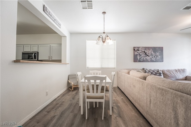 dining area with a notable chandelier and dark hardwood / wood-style floors