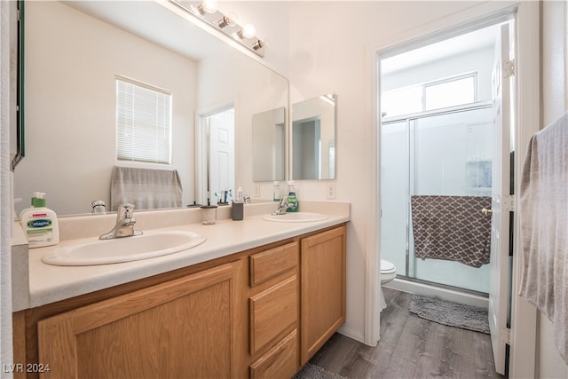 bathroom featuring toilet, hardwood / wood-style flooring, a shower with shower door, and vanity