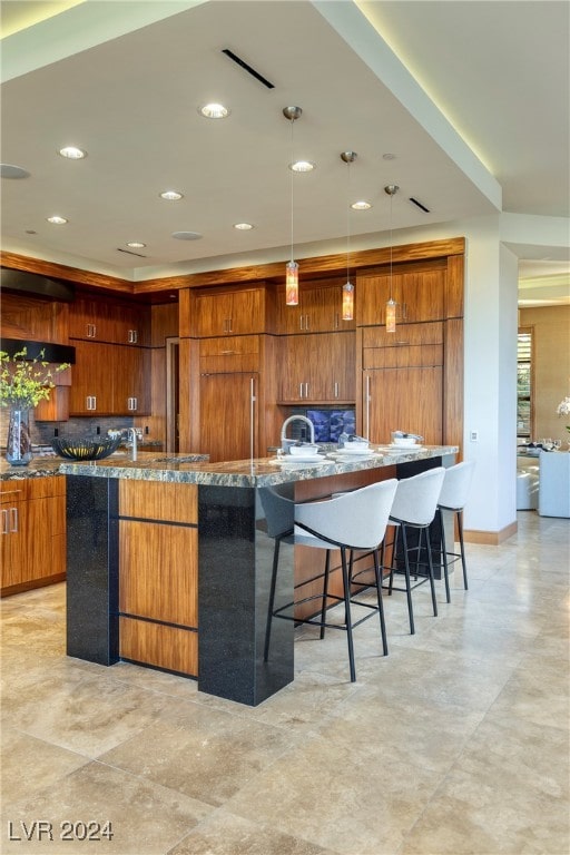 kitchen with a spacious island, a kitchen bar, pendant lighting, and backsplash