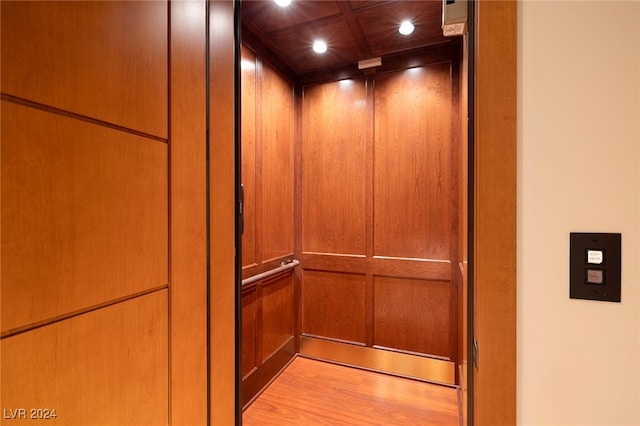 interior details featuring elevator, hardwood / wood-style flooring, and wood walls