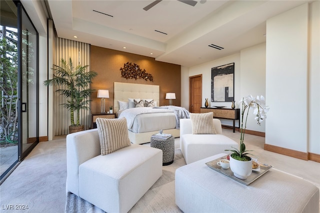 carpeted bedroom with ceiling fan, a tray ceiling, and access to exterior