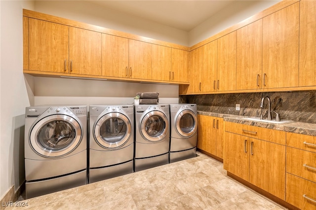 laundry area with cabinets, independent washer and dryer, and sink