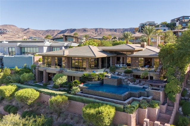 back of house with a balcony, a mountain view, a patio area, and a jacuzzi