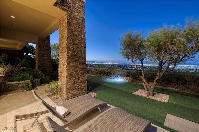 patio terrace at dusk featuring a lawn